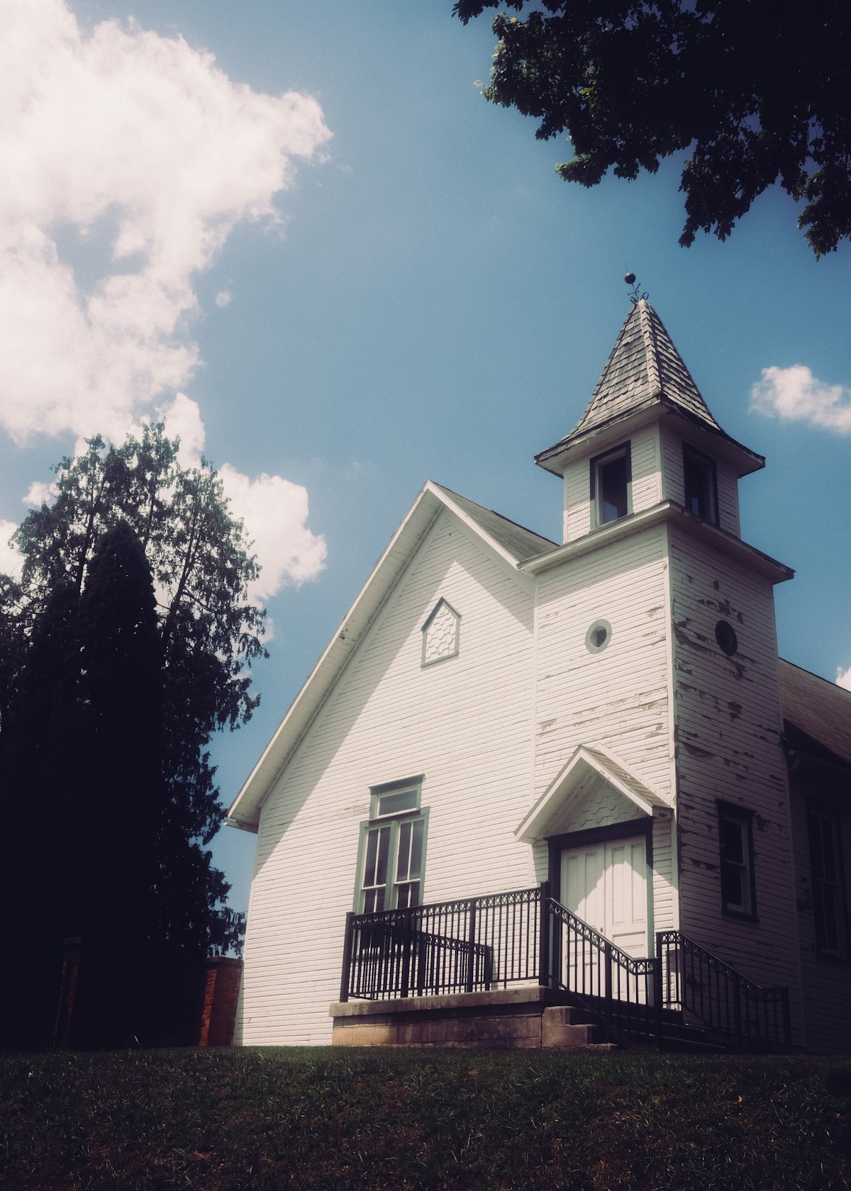 A weathered white church building against a bright blue sky